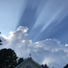 arduinna: photo of a dramatic blue sky with white clouds and dark sun stripes, above a roofline (blueskies)