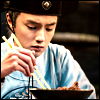 Tang Fan eating from a bowl with his pale green jade chopsticks